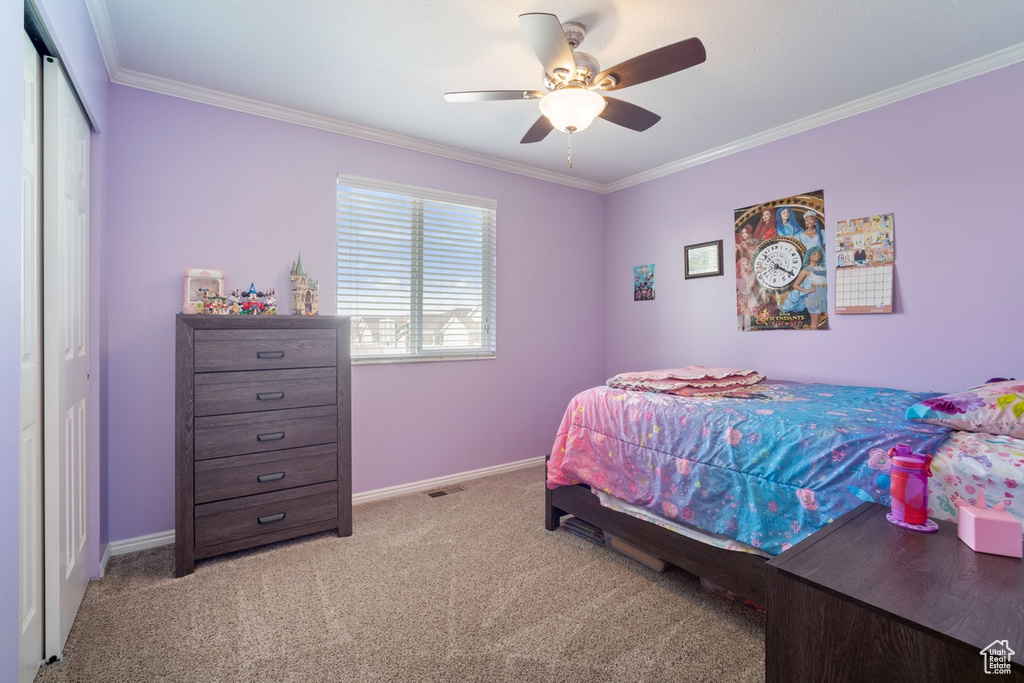 Bedroom featuring a closet, crown molding, a ceiling fan, light carpet, and baseboards