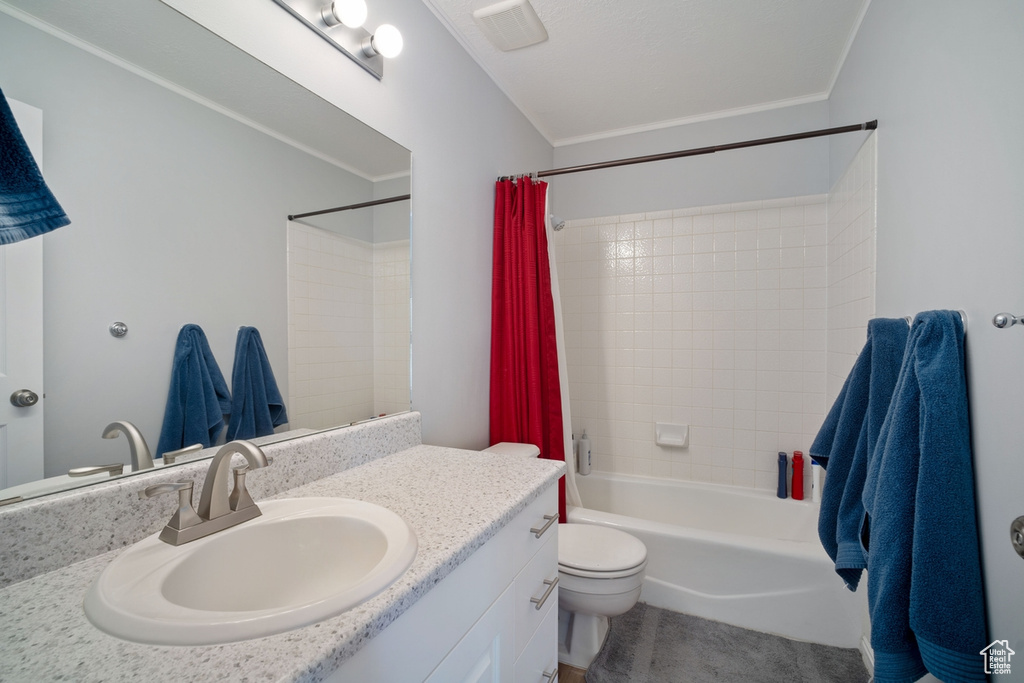 Bathroom with toilet, shower / bath combo with shower curtain, and vanity