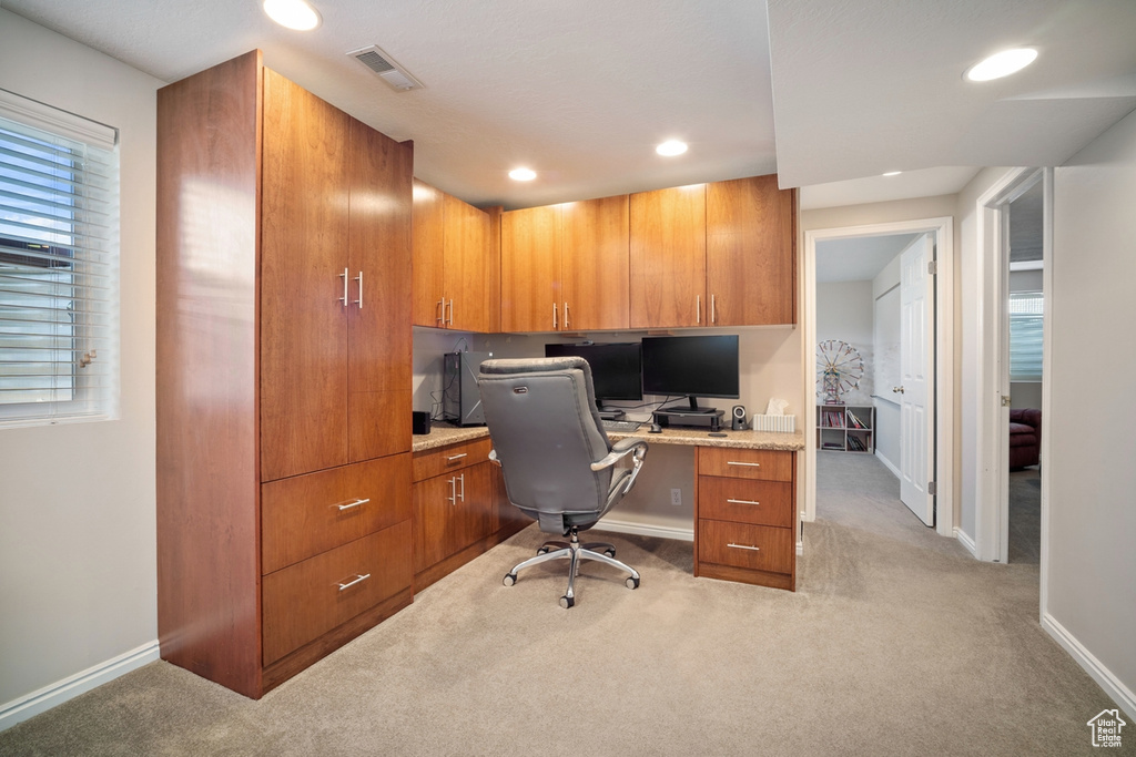 Office space with recessed lighting, visible vents, built in study area, baseboards, and light colored carpet
