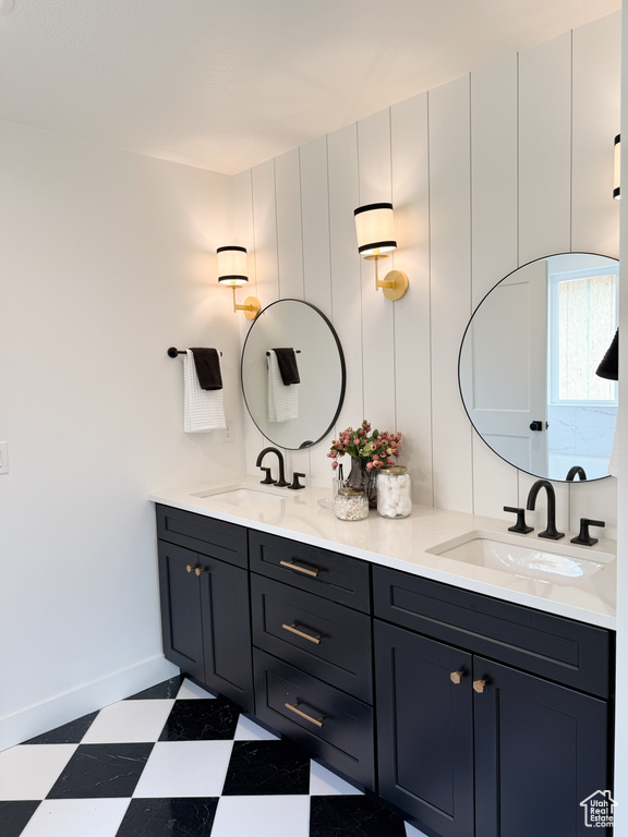 Bathroom with baseboards, double vanity, tile patterned floors, and a sink