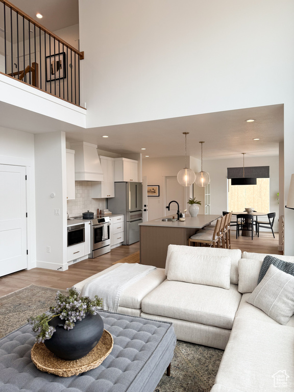 Living area featuring recessed lighting, a towering ceiling, and wood finished floors