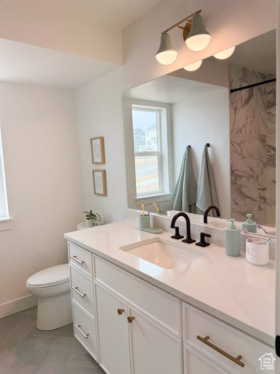 Bathroom featuring vanity, tile patterned flooring, a shower, toilet, and baseboards