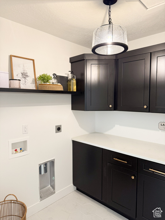 Clothes washing area featuring washer hookup, electric dryer hookup, a textured ceiling, cabinet space, and baseboards