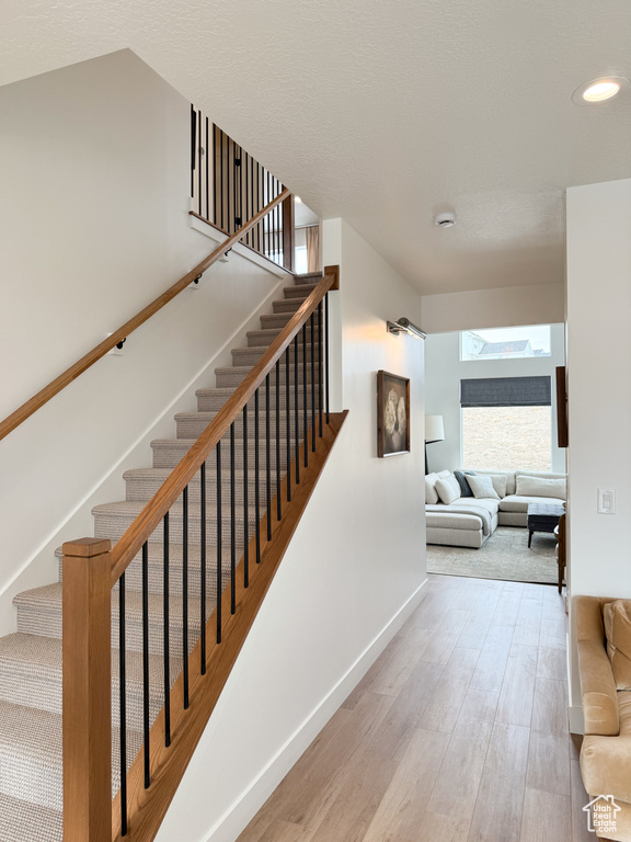 Stairway featuring baseboards, recessed lighting, and wood finished floors