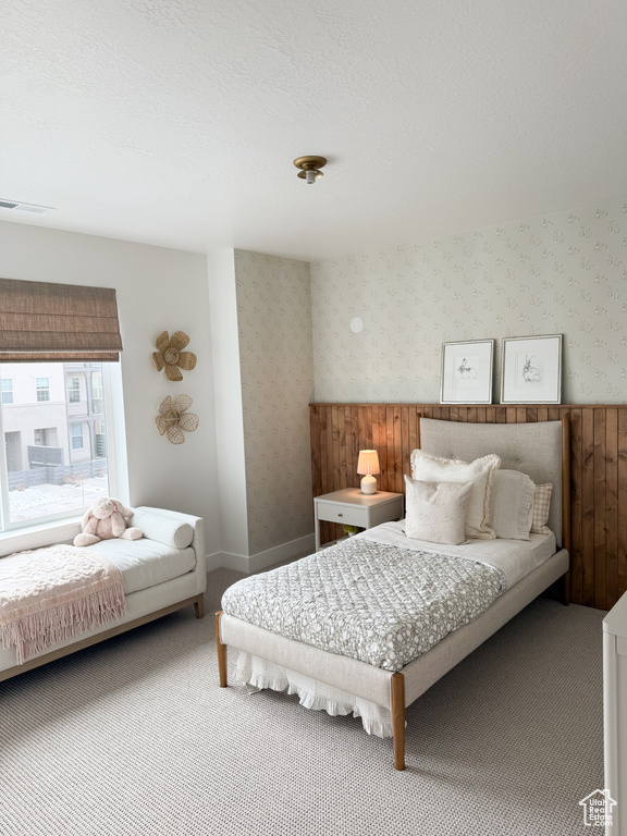 Bedroom featuring carpet flooring, wallpapered walls, and visible vents