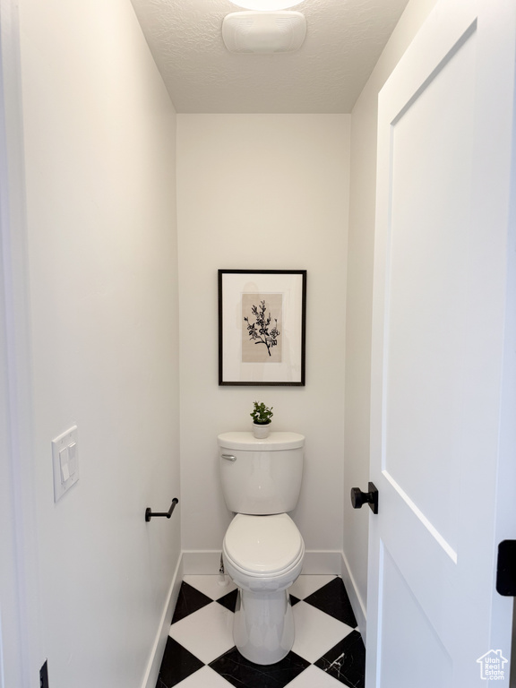 Bathroom with baseboards, tile patterned floors, and toilet