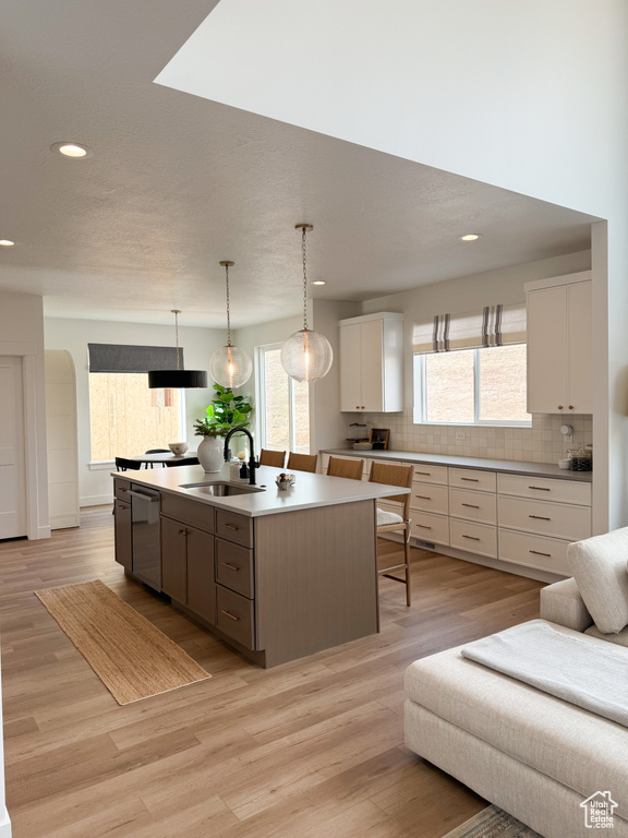 Kitchen with a sink, decorative backsplash, stainless steel dishwasher, and white cabinetry