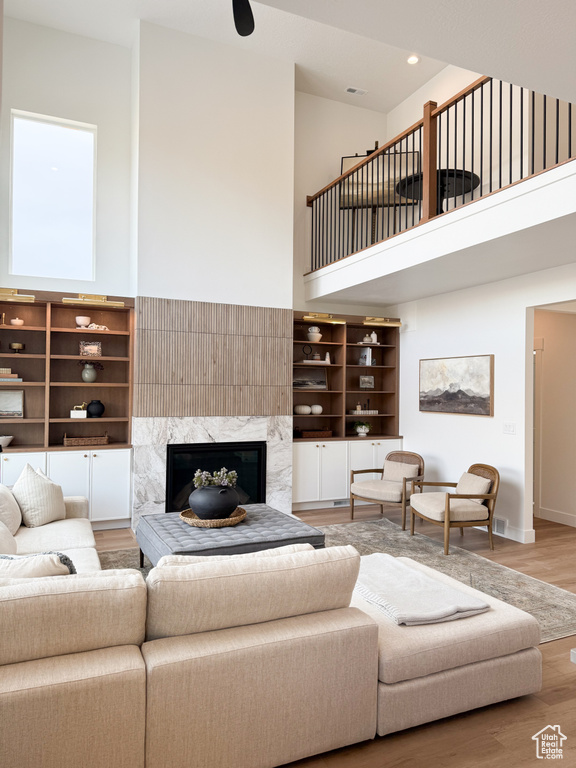 Living area featuring a high ceiling, a premium fireplace, recessed lighting, baseboards, and wood finished floors