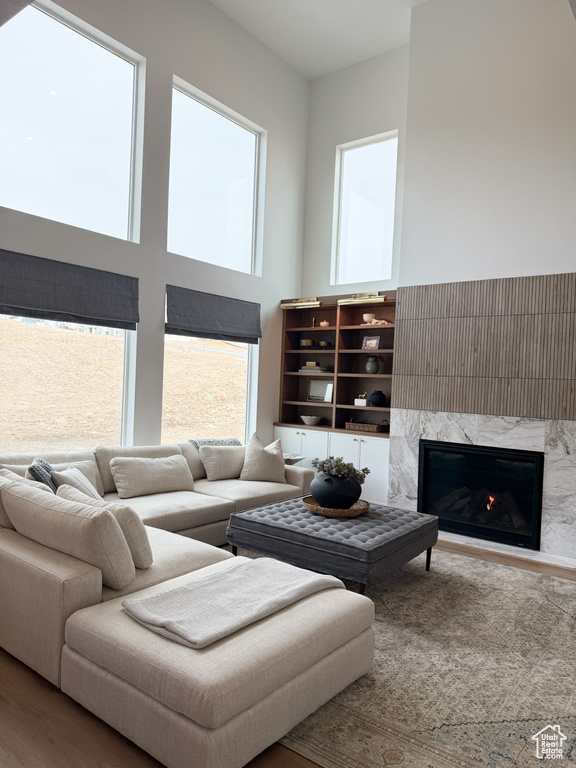 Living room featuring a towering ceiling, wood finished floors, and a fireplace