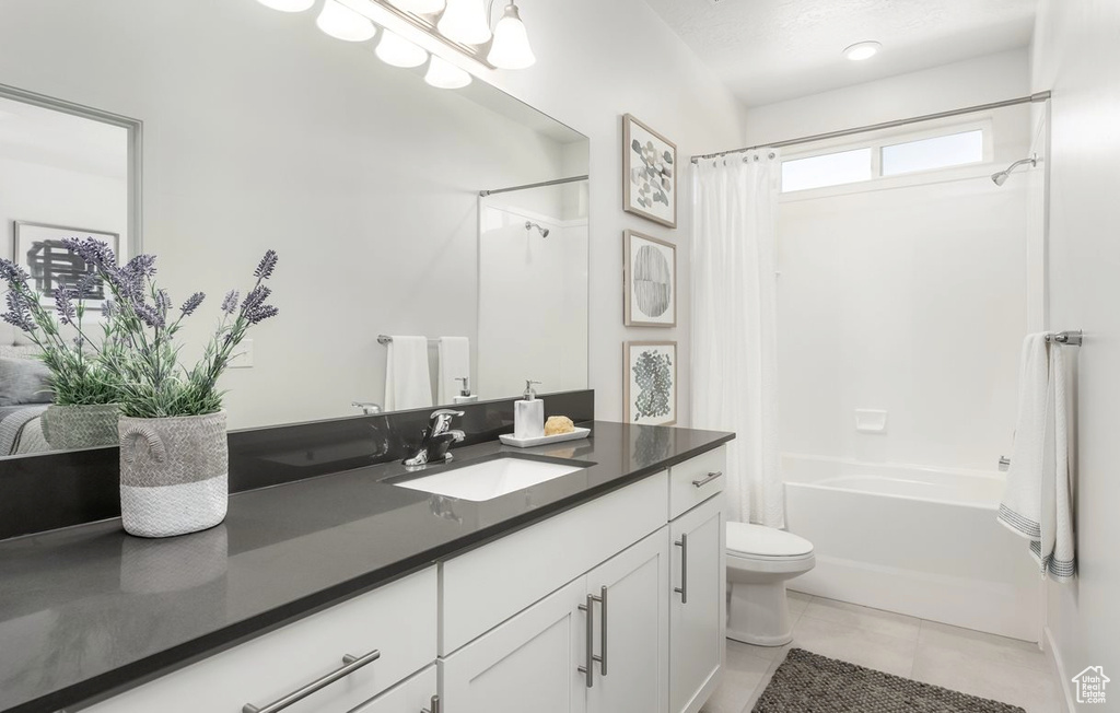 Bathroom featuring vanity, tile patterned floors, shower / bath combination with curtain, and toilet