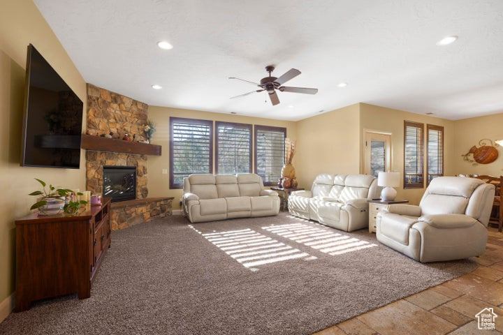 Living area featuring a ceiling fan, recessed lighting, a stone fireplace, and a healthy amount of sunlight