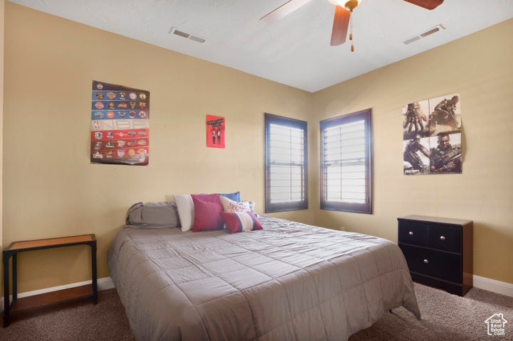 Carpeted bedroom featuring baseboards, a ceiling fan, and visible vents
