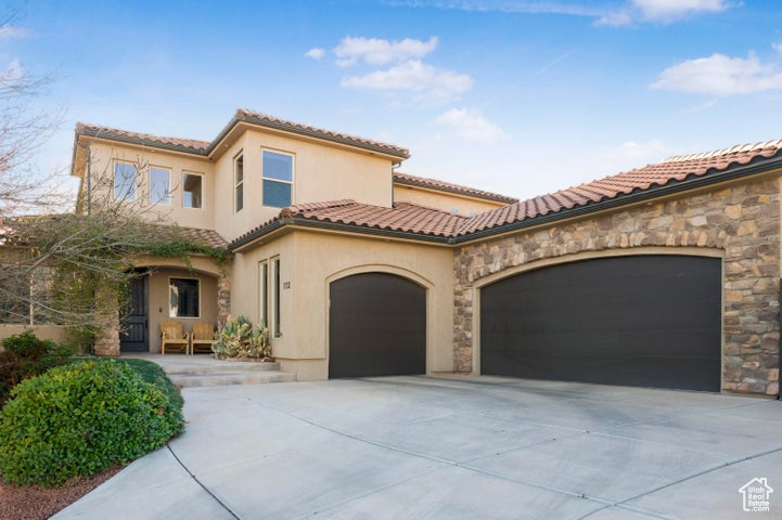 Mediterranean / spanish house featuring a garage, stone siding, stucco siding, driveway, and a tile roof