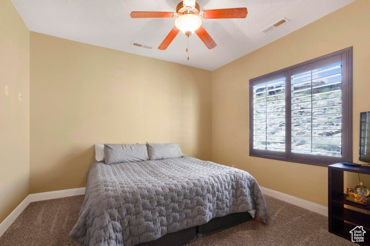 Bedroom featuring a ceiling fan, baseboards, visible vents, and carpet