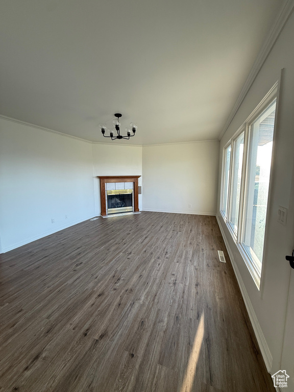 Unfurnished living room featuring visible vents, crown molding, dark wood finished floors, baseboards, and a chandelier