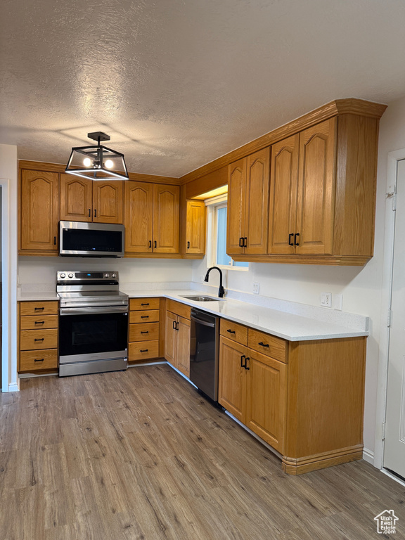 Kitchen featuring a sink, appliances with stainless steel finishes, light wood finished floors, and light countertops