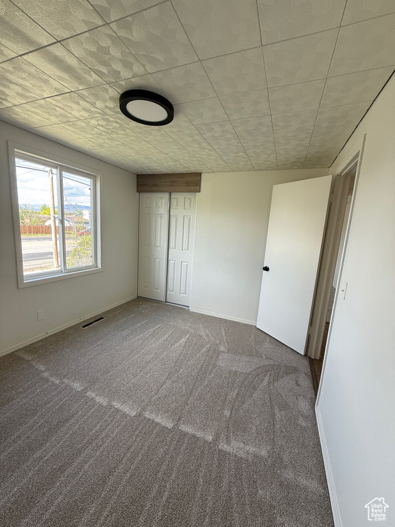 Unfurnished bedroom featuring carpet floors, baseboards, visible vents, and a closet