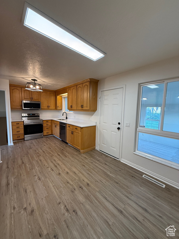 Kitchen featuring appliances with stainless steel finishes, a sink, light countertops, wood finished floors, and visible vents