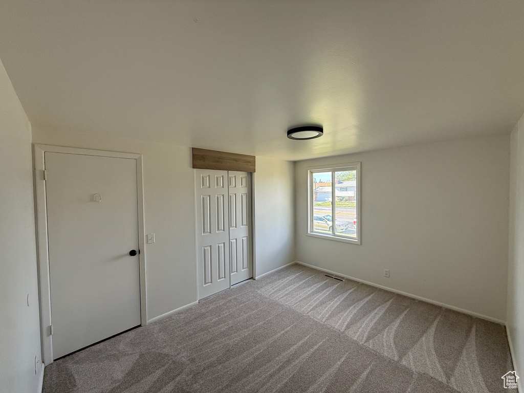 Unfurnished bedroom featuring baseboards, visible vents, carpet, and a closet