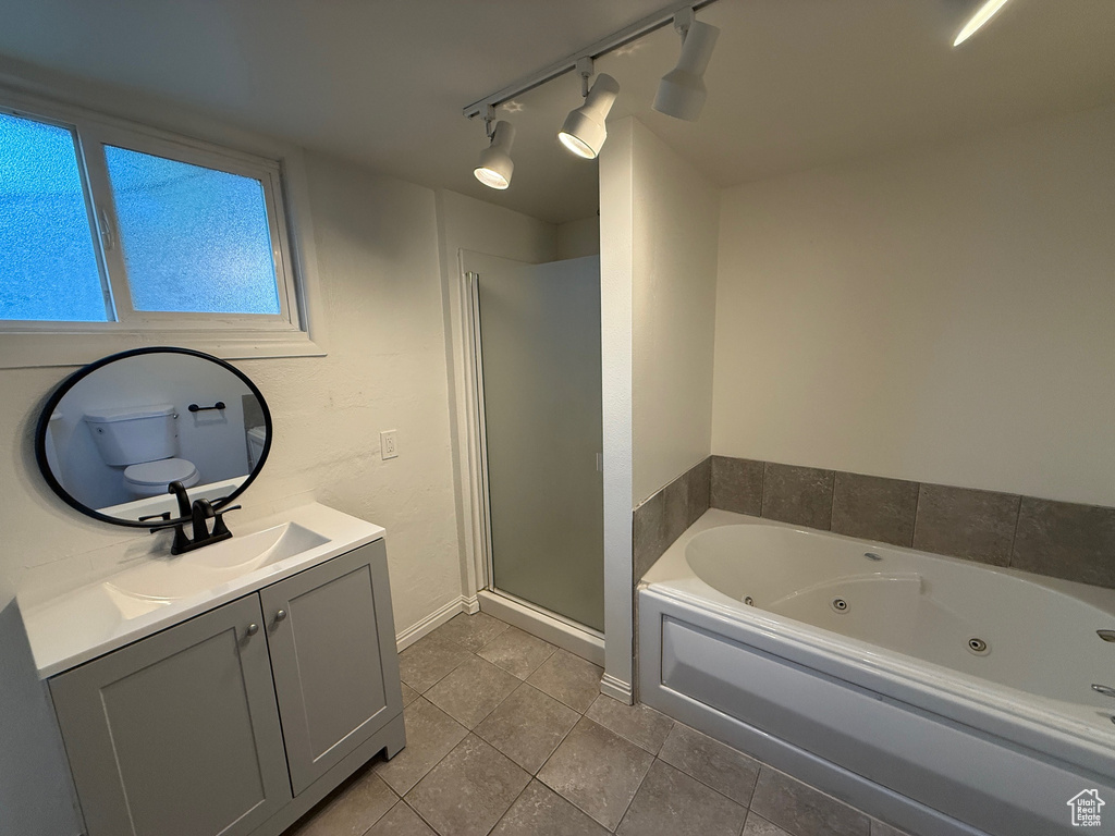 Full bathroom with track lighting, tile patterned flooring, vanity, a jetted tub, and a stall shower