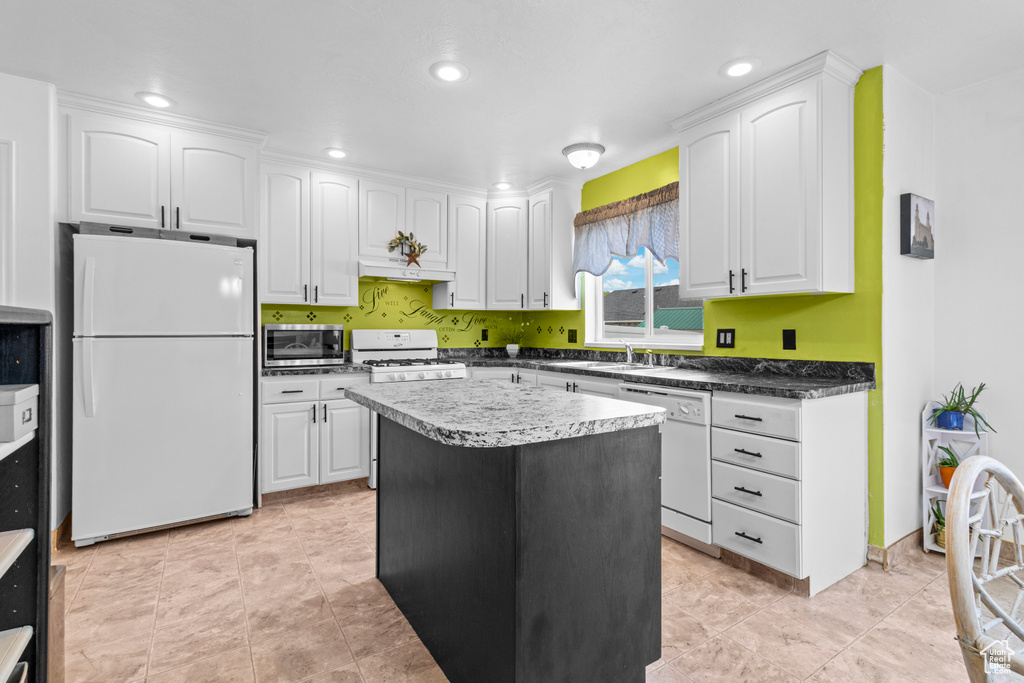 Kitchen featuring a sink, white cabinetry, a kitchen island, and white appliances
