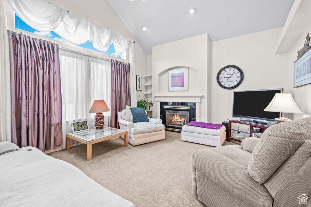 Carpeted living room with high vaulted ceiling and a tile fireplace