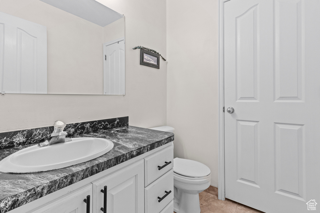 Half bath with vanity, tile patterned flooring, and toilet