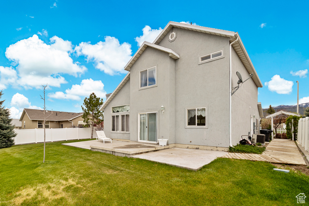 Rear view of property featuring a patio, a fenced backyard, stucco siding, central air condition unit, and a yard