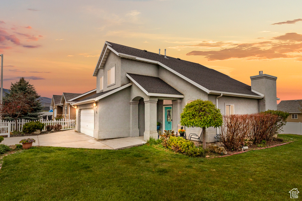 View of front of home featuring fence, driveway, a front yard, and stucco siding