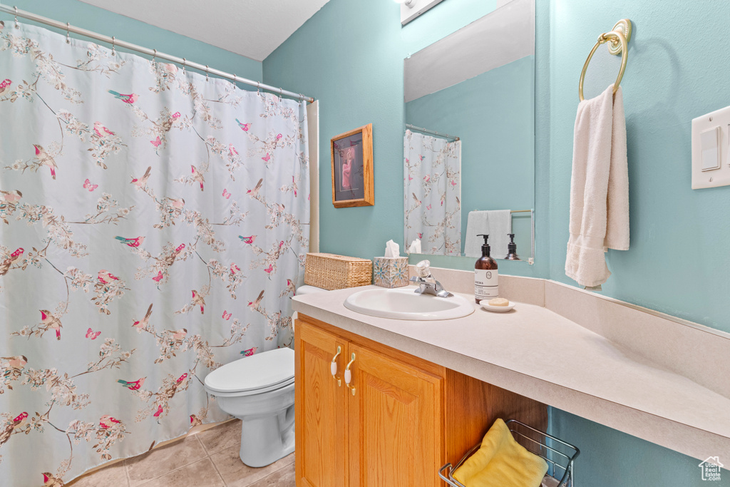 Bathroom with tile patterned floors, vanity, toilet, and curtained shower