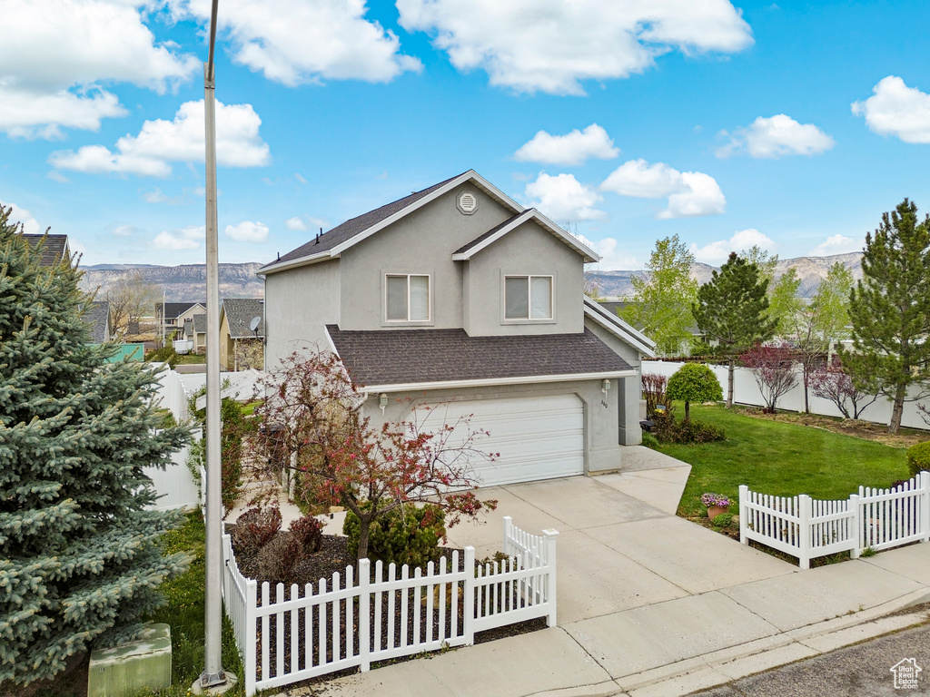 Traditional home with a garage, a front lawn, stucco siding, a shingled roof, and concrete driveway