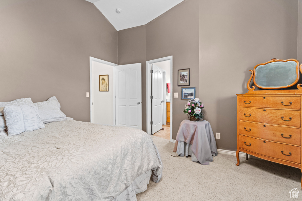 Bedroom with carpet floors, high vaulted ceiling, baseboards, and ensuite bath