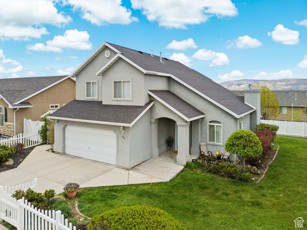 Traditional-style home featuring fence private yard, a shingled roof, stucco siding, and a front yard