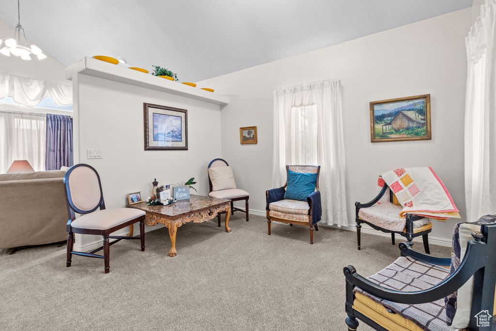 Sitting room with a notable chandelier, plenty of natural light, vaulted ceiling, and light carpet