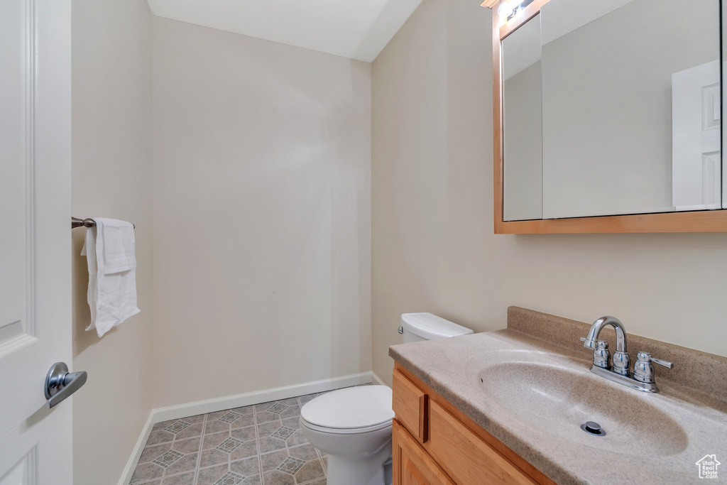 Half bathroom with baseboards, toilet, and vanity