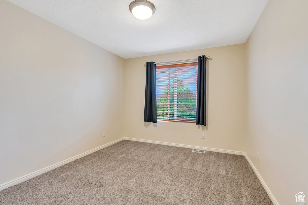 Carpeted spare room with baseboards and visible vents