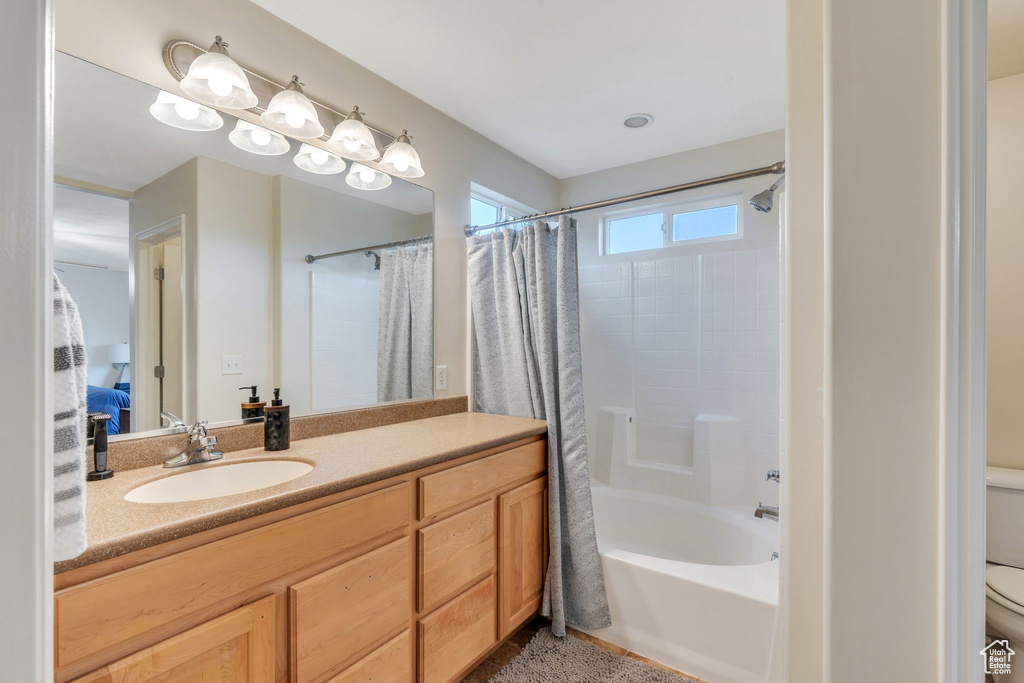 Bathroom with vanity, shower / bathtub combination with curtain, and toilet