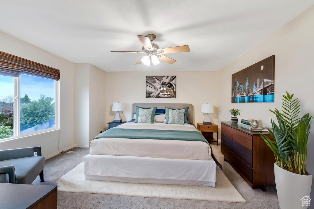 Bedroom with light colored carpet, baseboards, and ceiling fan