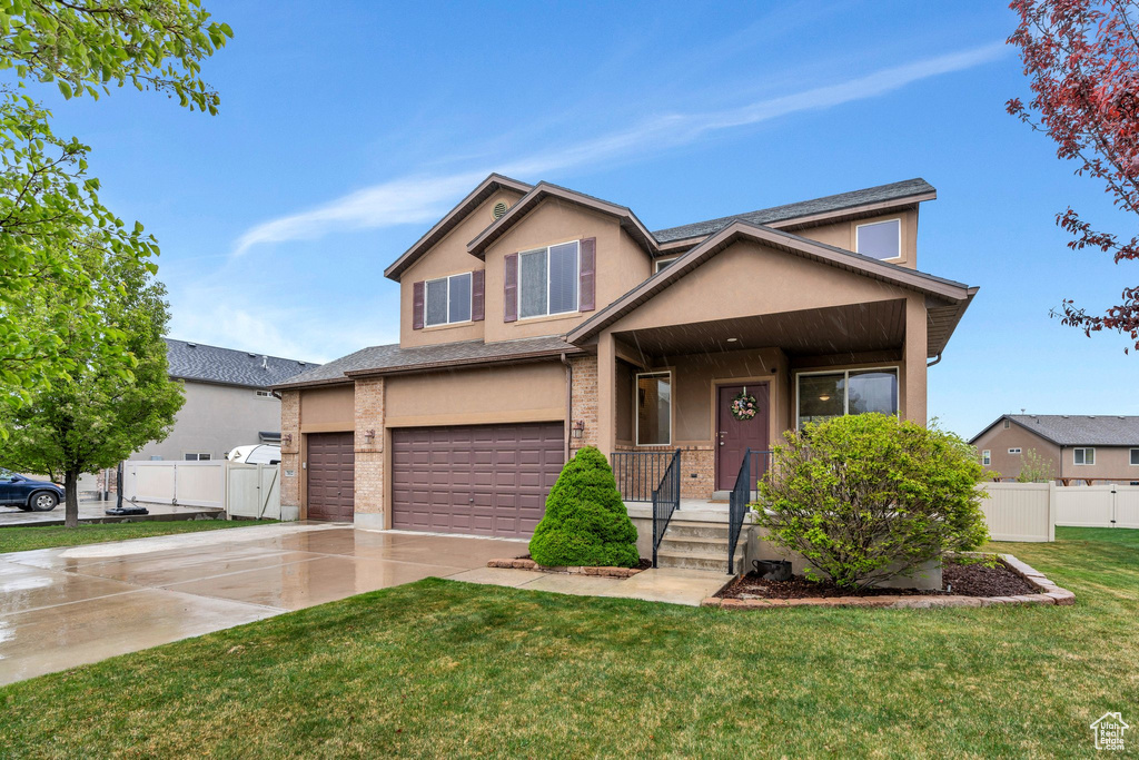 Craftsman-style home featuring covered porch, a front yard, a garage, fence, and stucco siding