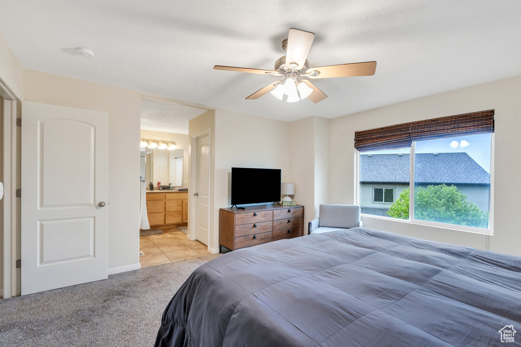 Bedroom with ensuite bathroom, baseboards, ceiling fan, and light carpet