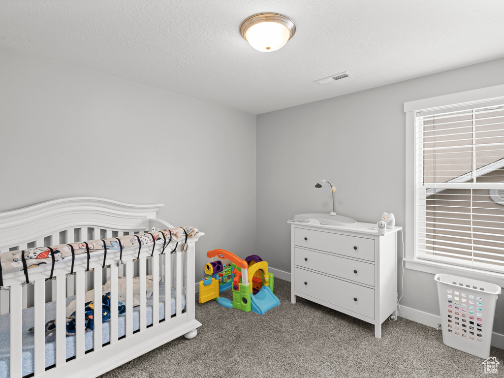 Bedroom featuring carpet flooring, a nursery area, baseboards, and multiple windows