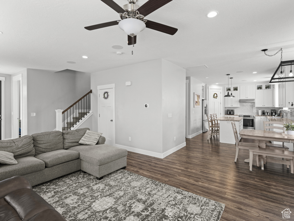 Living area featuring recessed lighting, baseboards, a ceiling fan, and dark wood-style flooring