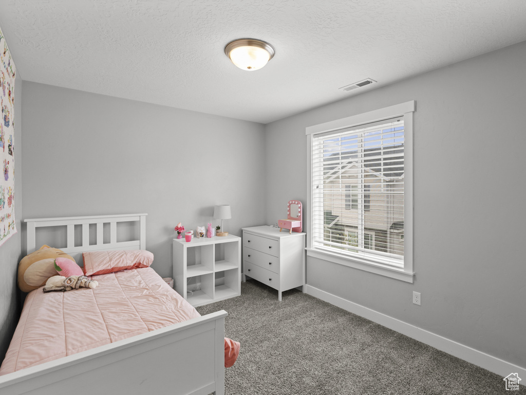 Bedroom featuring a textured ceiling, baseboards, visible vents, and carpet