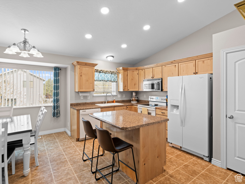 Kitchen featuring a sink, light brown cabinetry, white appliances, and a healthy amount of sunlight