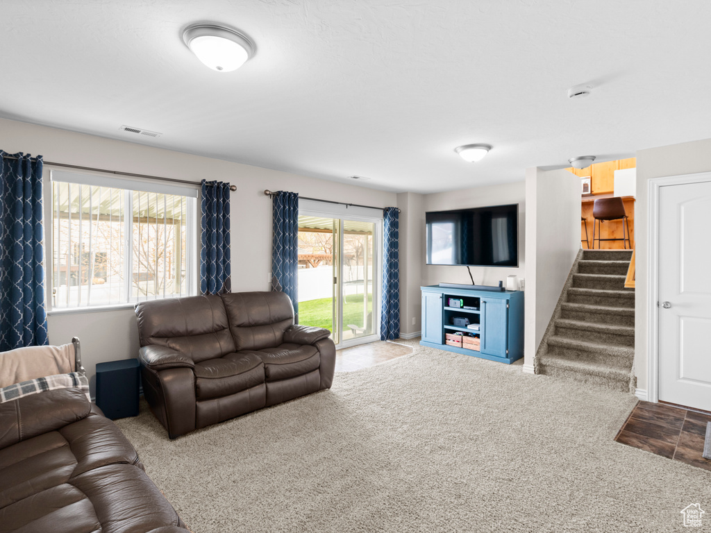 Living room featuring carpet floors, visible vents, and stairway