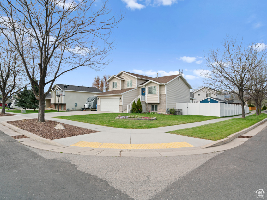 Traditional-style home featuring fence, a front yard, concrete driveway, an attached garage, and a residential view