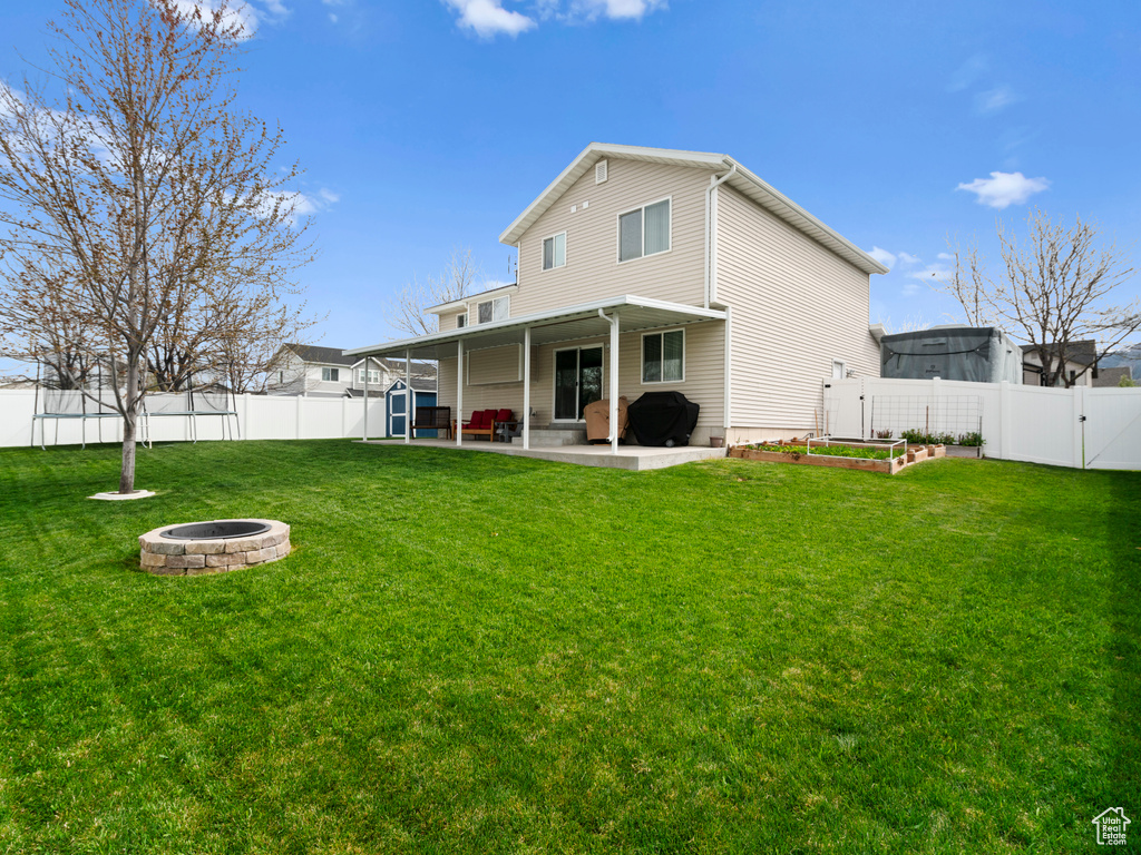 Rear view of house featuring a fire pit, a fenced backyard, a gate, a patio area, and a yard