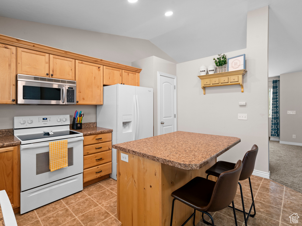 Kitchen with a breakfast bar, white appliances, recessed lighting, lofted ceiling, and a kitchen island