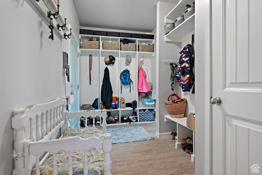 Mudroom with baseboards, a textured ceiling, and wood finished floors