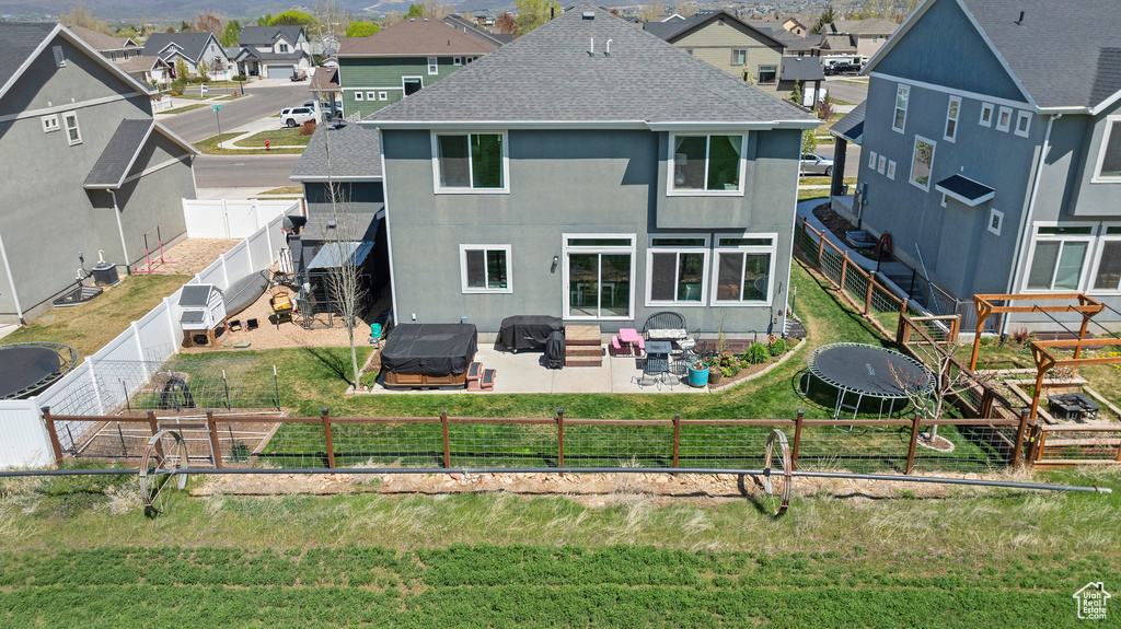 Rear view of house with roof with shingles, a fenced backyard, a patio area, and a residential view